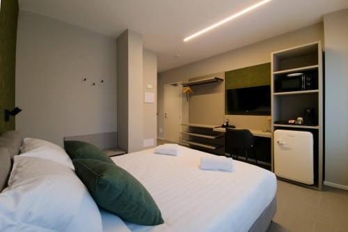 Camera Malachite presso SMalL Guesthouse a Bussolengo con letto queen, cuscino verde, scrivania moderna e angolo cottura
