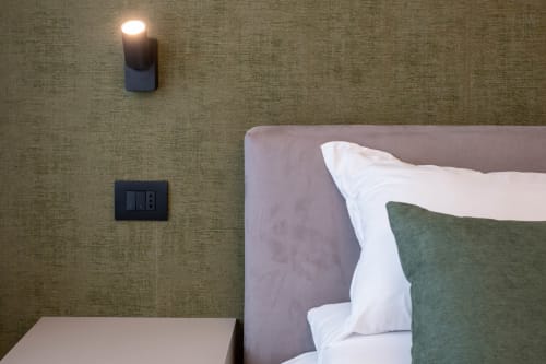 Camera moderna presso SMalL Guesthouse a Bussolengo con letto, cuscini, lampada a parete e interruttore