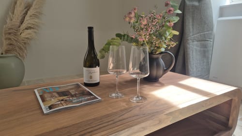 Wijnfles en glazen op houten tafel met roze bloemen en magazine in Moulin Renaudiots, Autun