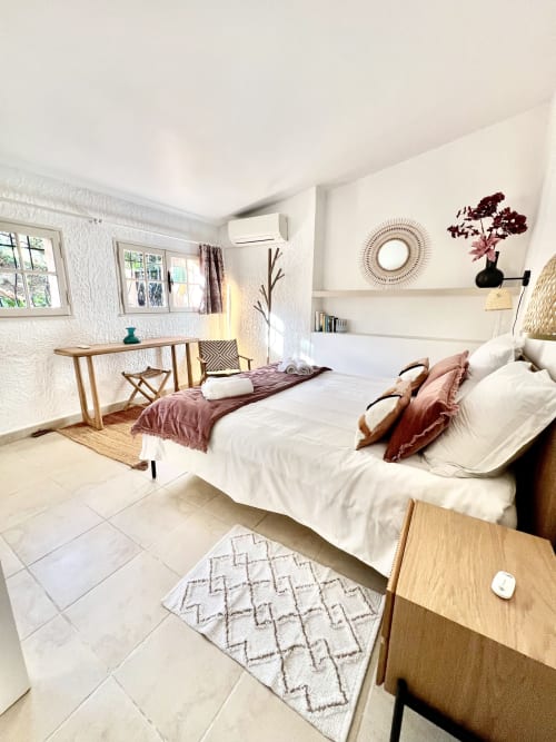 Bright bedroom at Capleouna villa in Cap d'Antibes with white bed, wooden desk, and shelving