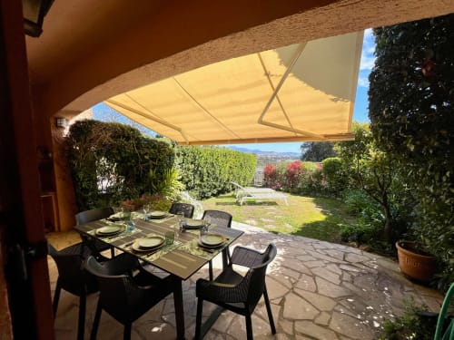 Elegant patio dining at Capleouna villa, Cap d'Antibes, with retractable awning, garden seating, and Mediterranean views
