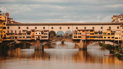 Ponte Vecchio che attraversa l'Arno a Firenze, con edifici storici e architettura dorata