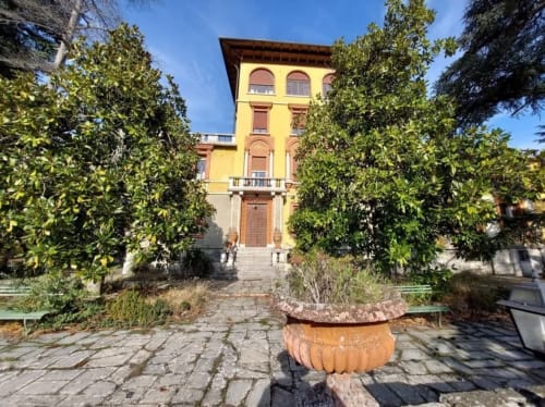 Palazzo Losio à Ponzone, Italie : élégant palais Renaissance jaune aux fenêtres cintrées encadré d'une entrée couverte de lierre