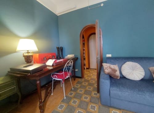 Suite chambre bleue avec bureau, chaise rouge, armoire en bois et canapé bleu au Palazzo Losio à Ponzone