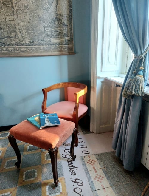 Espace salon de la suite au Palazzo Losio avec fauteuil corail, pouf et rideaux bleus à Ponzone
