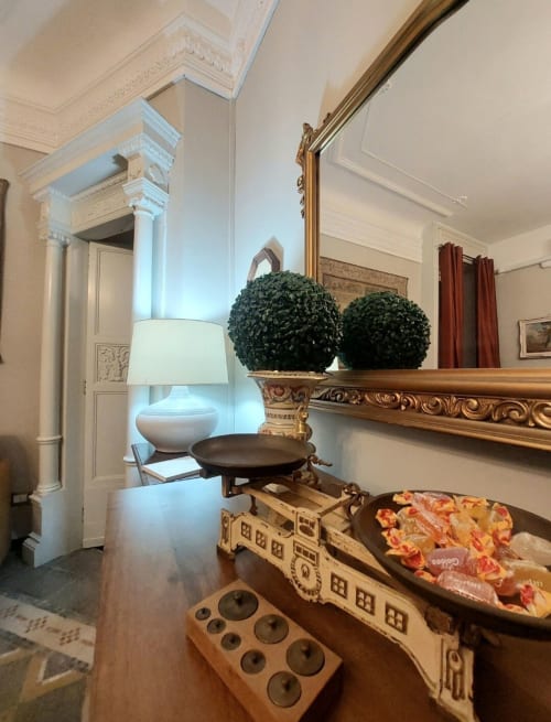 Entrée élégante de suite au Palazzo Losio avec décor classique, miroir orné, plantes en topiaire et mobilier d'époque