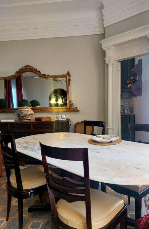 Élégante salle à manger de la suite Palazzo Losio avec table en marbre, chaises en bois foncé, miroir orné et moulures blanches
