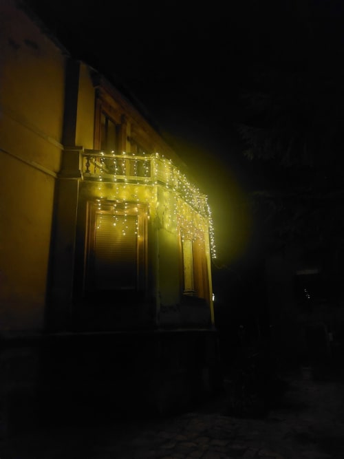 Entrée de la suite Palazzo Losio de nuit, décorée de guirlandes lumineuses blanc chaud drapant le balcon et l'entrée.