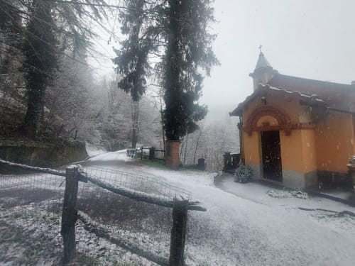 Petite chapelle enneigée près du Palazzo Losio à Ponzone, Italie, entourée d'arbres couverts de lierre