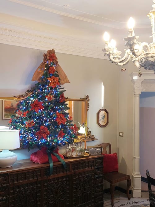 Salle de bains élégante du Palazzo Losio avec un sapin de Noël festif orné de lumières bleues et de poinsettias rouges