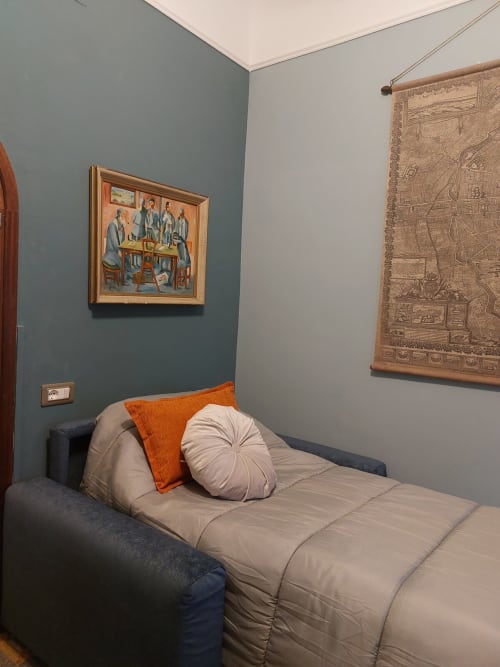 Chambre accueillante au Palazzo Losio avec mur d'accent bleu-vert, lit avec coussin orange, œuvres d'art encadrées et tapisserie à Ponzone, Italie