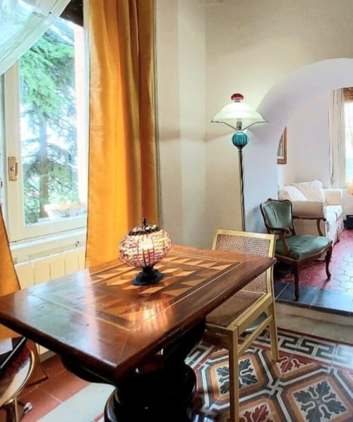 Élégante salle à manger avec table en bois, lampe en vitrail et vue sur le jardin au Palazzo Losio en Piémont, Italie