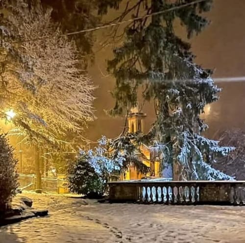 Nuit d'hiver enneigée au Palazzo Losio dans le Piémont, église illuminée et arbres givrés