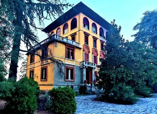 La villa historique jaune du Palazzo Losio entourée de grands arbres et de jardins paysagés à Ponzone, Piémont
