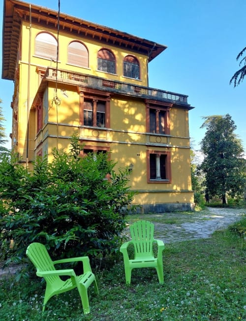 Villa italienne jaune éclatant avec chaises Adirondack vertes dans le jardin du Palazzo Losio, Piémont