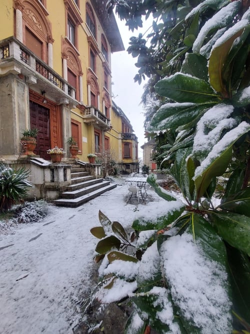 Cour enneigée du Palazzo Losio avec ses bâtiments historiques jaunes, cactus et paysage hivernal du Piémont