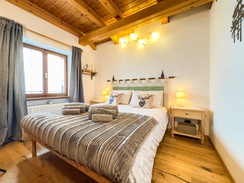 Alpine bedroom with wooden beams, striped bedding, mountain view window, and rustic deer décor at Belvedere Solferino, Santo