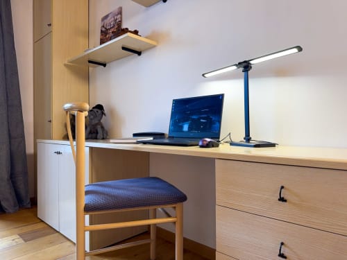 Modern workspace in Belvedere Solferino apartment with desk, laptop, blue desk lamp, wooden chair, and mountain views in