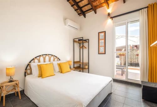 Chambre lumineuse à l'hôtel Casa Sibarita à Rafelguaraf avec accents jaunes, literie blanche, accès terrasse et design moderne