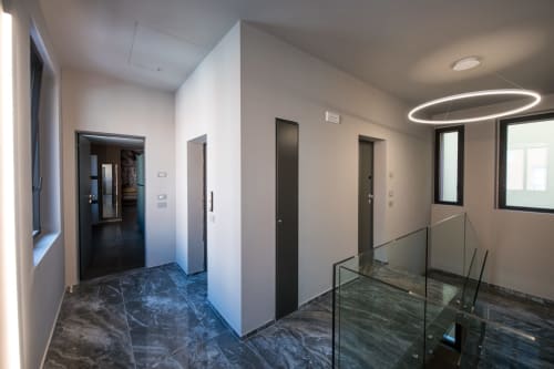 Corridoio moderno della Suite Sibilla presso Manu Maison a Parma, con pavimenti in marmo, ringhiera in vetro e design contemporaneo