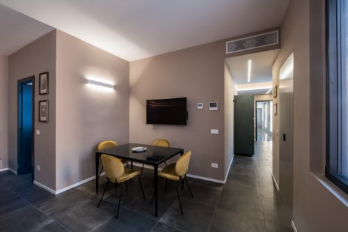 Moderno appartamento Sibilla Suite a Parma con tavolo da pranzo, sedie gialle, TV a parete e arredamento contemporaneo