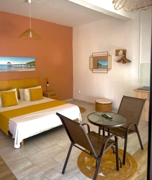 Chambre Studio Lagon du Kaz Kafe à Mamoudzou avec vue mer, lit jaune, coin salon et mobilier contemporain