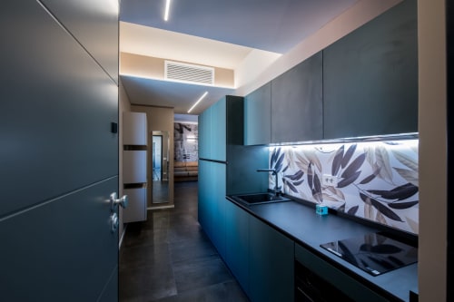 Cucina moderna nella suite Sibilla di Manu Maison a Parma, con mobili teal, piani neri e dettagli decorativi