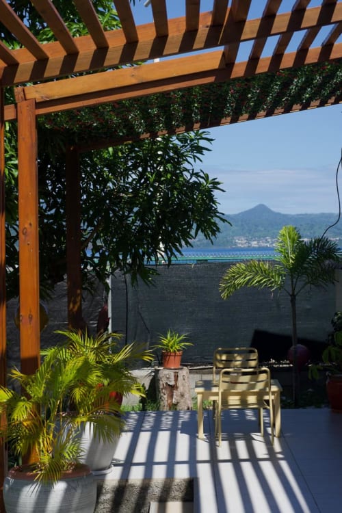 Terrasse Studio Lagon du Kaz Kafe avec pergola en bois, plantes tropicales et vue sur le lagon à Mamoudzou