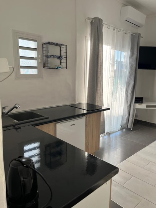 Studio Océan kitchenette with black countertop, sink, and sea view at Kaz Kafe, Mamoudzou