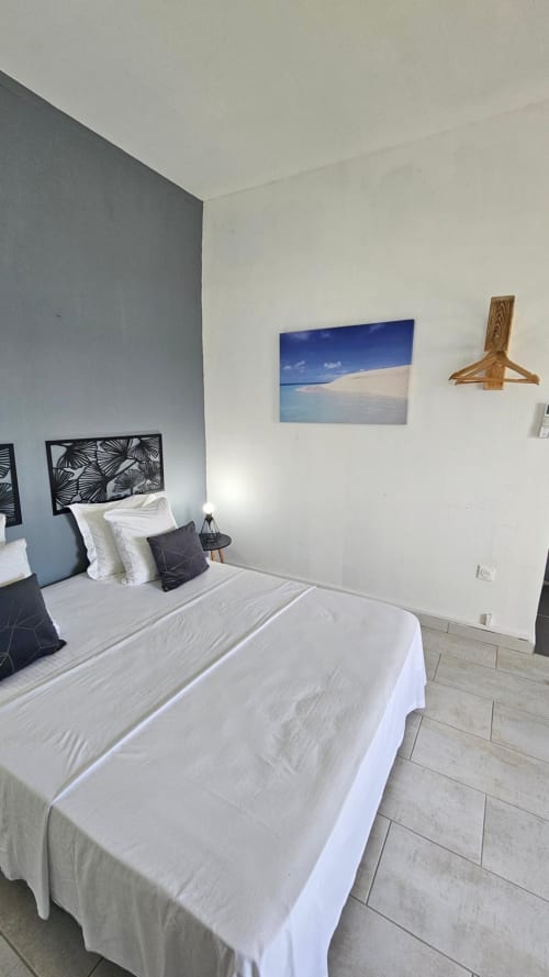Studio Océan bedroom at Kaz Kafe, Mamoudzou, with sea view canvas, white bedding, and modern décor