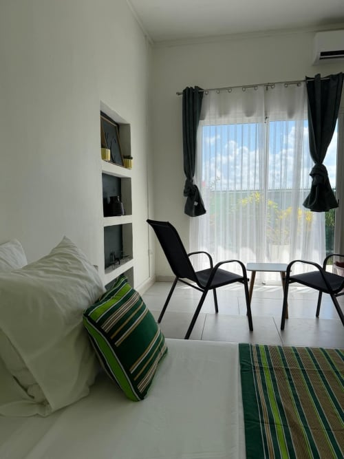 Studio Continent at Kaz Kafe in Mamoudzou features modern seating, white bedding with green striped pillows, and sea views