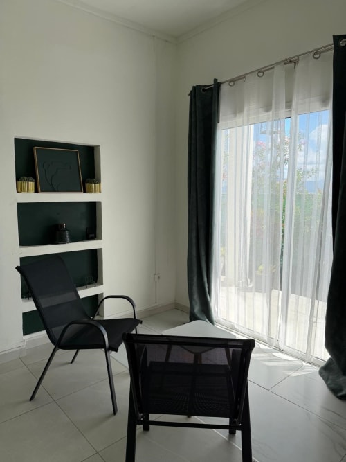 Modern studio apartment at Kaz Kafe with black seating, shelving, and sea view doors in Mamoudzou