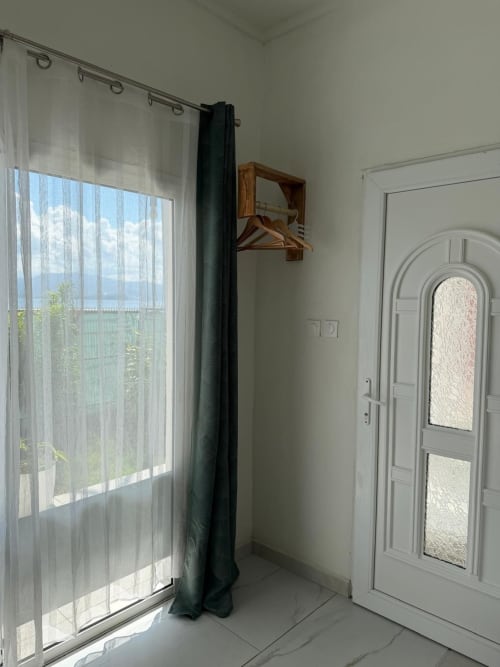 Studio Continent at Kaz Kafe B&B in Mamoudzou with sea view, sheer curtains, dark drapes, wooden shelf, white door, and tiled