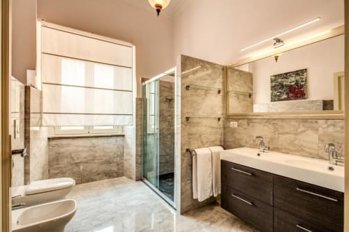 Lussuoso bagno in appartamento romano con doccia in marmo, doppio lavabo e finiture moderne