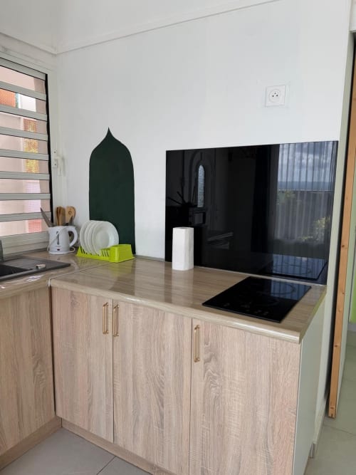 Modern kitchen in Kaz Kafe studio apartment, Mamoudzou, with wooden cabinets, black cooktop, and sea view