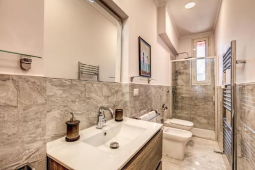 Bagno moderno con piastrelle in marmo, lavabo bianco, toilet e doccia walk-in presso l'appartamento Downtown Srl a Roma