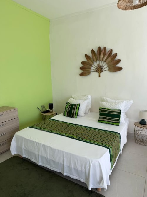 Studio Continent bedroom at Kaz Kafe with lime green accent wall, white bedding, green striped pillows, and decorative palm
