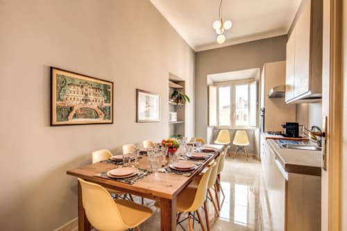 L'affascinante appartamento retrò a Roma dispone di una sala da pranzo mid-century con tavolo in legno, sedie gialle e cucina moderna