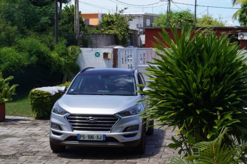 Hyundai argentée garée dans le jardin de la villa Kaz Kafe BnB à Mamoudzou avec plantes tropicales