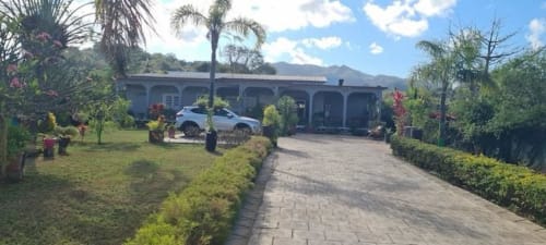 Gîte Kaz Kafe à Mamoudzou, vue sur le jardin, allée pavée, voiture bleue, palmiers et montagnes