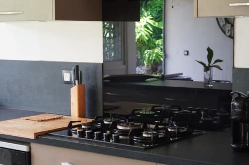 Cuisine moderne du gîte Kaz Kafe à Mamoudzou avec cuisinière à gaz noire, planche à découper en bois, bloc à couteaux et vue sur le jardin
