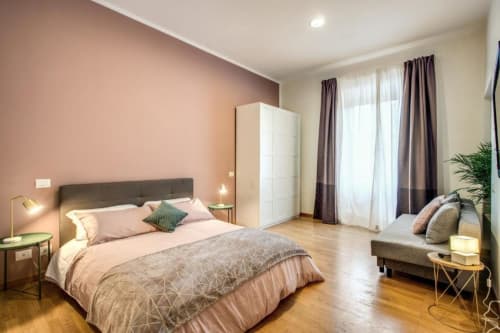 Camera da letto spaziosa dell'appartamento Diocleziano Triple a Roma con letto matrimoniale, armadio bianco, pavimenti in legno e arredi moderni
