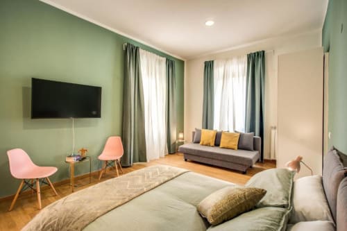 Spaziosa camera da letto dell'appartamento Diocleziano Triple a Roma con letto matrimoniale, divano, TV e pareti verdi