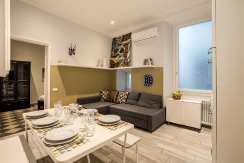 Appartamento moderno a Roma con tavolo da pranzo, divano grigio scuro e parete accent oliva in living open-plan