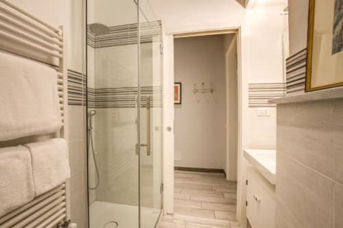 Bagno moderno con box doccia in vetro, scaldasalviette e lavabo nell'appartamento di Roma