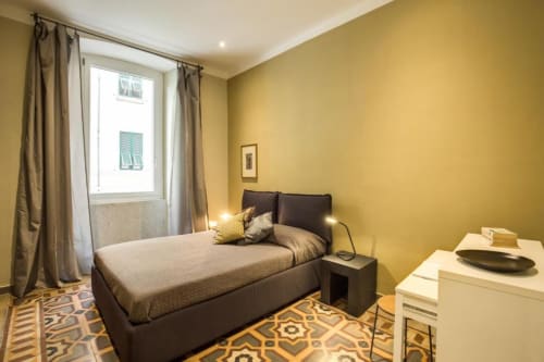 Camera da letto gialla luminosa con letto matrimoniale, vista sulla città e arredi moderni in appartamento a Roma