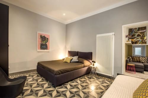 Camera da letto moderna nell'appartamento Cavour Cinque Terre a Roma, con letto scuro, pareti grigie, pavimento geometrico e spazio aperto