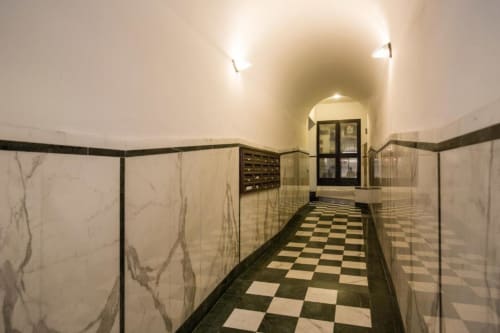Elegante corridoio con pavimento in marmo bianco e nero a scacchi e pareti in marmo crema nell'appartamento Downtown Srl a Roma