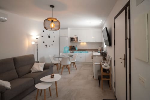 Apartamento moderno de planta abierta en Setenil de las Bodegas con sofá gris, comedor y cocina equipada