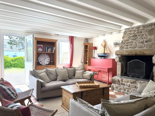Spacieux séjour de la villa Soleilmeretsable à Hoëdic avec cheminée, baie vitrée vue mer, canapé gris et décoration marine